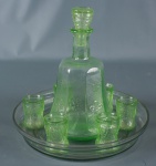 Conjunto de licoreira em vidrão verde com 6 copinhos. Acompanha um prato de vidro transparente. Mede 22cm de altura.