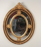 Grande espelho oval com dupla moldura dourada. Mede 1,40m x 1,10m. 