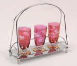 Três copos de cristal vermelho lapidados e um suporte em metal cromado. Mede o suporte 10cm largura e o copo 11cm de altura.