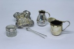 Quatro peças sendo duas mini leiteiras em metal espessurado a prata e porta comprimido em cristal e tampa em prata alemã contrastada e coador de chá em prata.