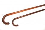 Duas bengalas em madeira maciça, castão em arco. Comprimento: 93 cm e 90 cm.