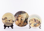 Lote constando três pratos decorativos em porcelana com rica policromia decorados com " Anjos". Med.: 25 cm, 21 cm e 19,5 cm.