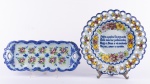 Lote constando duas peças em ceremâmica portuguesa na cor azul ricamente policromada com com esmaltes florais sendo uma travessa retangular e um prato decorativo. Med.: 3,5 x 42 x 16 cm e 34 cm. Obs.: travessa com discretos bicados.