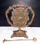 Gongo de mesa em bronze com seu respectivo batedor, ricamente decorado por volutas e flores, mede 22,5 x 19,5 cm.
