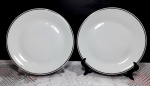 2 pratos em porcelana branca com borda em filetação prateada. Medem 25 cm de diâmetro cada.