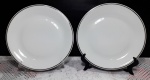 2 pratos em porcelana branca com borda em filetação prateada. Medem 25 cm de diâmetro cada.