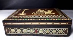 Caixa marroquina em madeira marchetada decorada por imagem de palmeira e camelo e detalhes em madreperola. Mede 4,5 cm de altura / 12,5 cm de largura por 16 cm de comprimento. Possui marcas do tempo.