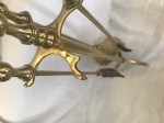 Kit para lareira em metal dourado com acabamento em forma de cabeça de cavalo, apoiado sobre três pés. Med.: 72x14x14. OBS: Falta uma ponta no suporte.