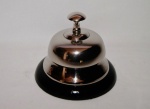 Campainha de metal tipo sineta com acionamento por botão superior com a base em formato arredondo na cor preto. Peça sem uso e na caixa original
