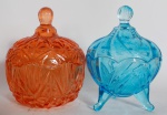 Lote de duas pequenas bombonieres em vidro nas cores azul e laranja em perfeito estado. Medida: 13 cm x 9,5 cm; Laranja: 13 cm x 10,5 cm
