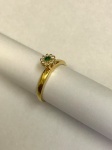 JOIA- Delicado anel em ouro 18k, modelo flor, cravejado por brilhantes, galeria central composta por pedra esmeralda. Aro. 13