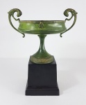 Elegante vaso em bronze ao gosto neo clássico MEDICI, montado sobre base em metal pintado na cor negra e pátina esverdeada. Med. 26 x 22 cm