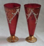Lote constando de 2 flutes venezianos em vidro moldado no tom rubi decorado com volutas e folhagens a ouro.
