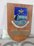 Placa em madeira  com símbolo esmaltado do III Comar RJ. Med. total 17 x11 cm