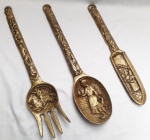 trio de peças decorativas em bronze, com cena Holandesa, sendo: 1 grande Colher, 1 faca e 1 grande garfo. Med maior: 41,5 x 8,5 cm.