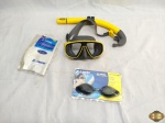 Lote de mergulho composto de 1 máscara de mergulho, 1 óculos de natação, 1 respirador e 1 touca. A máscara de mergulho está com o elástico solto.