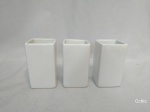 3 peças cporta trecos brancos com base quadrada em porcelana . Medida: 10cm de altura x 6x6cm de base. Um dos cachepots apresenta bicado