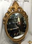 Espelho oval com moldura em madeira com patina ouro. Medindo a moldura 105cm x 66cm e o espelho 63cm x 53cm.