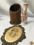 Lote composto de porta garrafa em madeira, vaso floreira em porcelana e camafeu de menina sobre seda em bronze. Medindo o porta garrafa 20cm de altura.