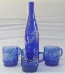 Uma garrafa em vidro azul com três canecas, com delicados desenhos pintado a mão - Altura: 31 cm e 9 cm