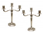 Par de candelabros ingleses para três velas, em "Silver Plate". Base quadrangular de cantos chanfrados assim como as bobeches, sustentadas por braços recurvos. Meados do século XX. 38 cm.