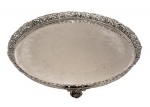 Grande bandeja de metal espessurado a prata. Formato circular, centro lavrado e grade vazada com decoração de botões de flores