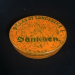 caixinha de lata ovalada de balas sortidas da Sonksen dos anos 60 na cor laranja medindo 3 cm de altura por 8,5 de comprimento por 6 de largura.