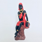 Estatueta em resina de mulher tribal Africana sentada na  rocha. Detalhe na vestimenta na cor vermelho e adereços em amarelo.Cabeça com restauro, nada que tire a beleza do exemplar. Dimensões: 30 cm x 12 cm / Aproximadamente. 2 kg.
