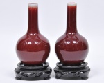 Par de vasos chineses em porcelana, conhecida como Sangue de Boi. Acompanha base em madeira torneada. Assinado no fundo. Med. 16  cm e 20 cm com a base.