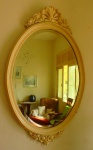 Epelho Oval com moldura em madeira laqueada na cor branca, entalhes de florais e arabescos, apresenta desgastes na peça. Med. 58cm x 93cm