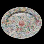 Travessa oval em porcelana chinesa com rica pintura com grande peônia central, flores, folhas e cachos de uva. Dinastia Qing (1644 - 1912). Diâmetro: