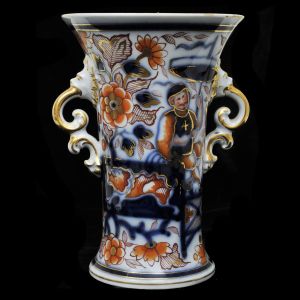 Vaso em porcelana inglesa em formato de corneta, decorado com pintura ao gosto Imari, com alças em caras de leão com volutas vazadas. Alt.: