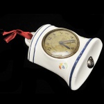 Relógio inglês de porcelana em formato de sino ao gosto do famoso `Big Ben`, mostrador em metal, máquina `WIND FULLY`, cerca de 1930/40. Medidas:  22 x 18,5 cm