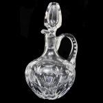 Garrafa licoreira em sólido cristal da Tcheckoslováquia, bojo globular com grandes reservas de esferas e folhas, tampa facetada e alça em lapidação dedão. Altura: 25 cm.
