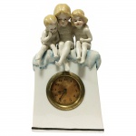 Relógio em porcelana, com decoração de crianças. Apresenta restauro. 20 x 12 cm.