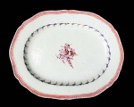 CIA DAS INDIAS  ELEGANTE TRAVESSA EM PORCELANA CIA DAS INDIAS (FORMA PAR IDENTICO COM A OFERTADA NO LOTE A SEGUIR) COM ESMALTES DA FAMILIA ROSA. REINADO QIANLONG (1711  1799). BORDA RECORTADA, DECORADA COM GREGA NA TONALIDADE ROSE DELIMITADA POR FILETES ROUGE DE FEUR. TRANSIÇÃO DA BORDA PARA A CALDEIRA COM GUIRLANDA EM AZUL COM PARRAS E CACHOS DE UVA. NA CALDEIRA RESERVA CONTENDO RAMALHETE FLORAL. FUNDO TEM CERÂMICA APARENTE. CHINA, SEC. XVIII. 27 CM DE COMPRIMENTO