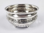 IMPORTANTE BOWL DE PINGOS EM PRATA DE LEI. CONSTRASTES PARA CIDADE DO PORTO, INICIO DO SEC. XIX. MARCAS DO PRATEIRO ANTONIO RODRIGUES DE ARAÚJO, ATIVO EM 1791 E TAMBÉM ENSAIADOR DO CONTRASTE DESSA PEÇA. ELEGANTE FEITIO CORPO DECORADO COM CERCADURA DE ENROLAMENTOS VEGETALISTAS EM RELEVO. TERÇO INFERIOR COM CANELURAS. ASSENTE SOBRE QUATRO PÉS EM BOLA. PORTUGAL, INICIO DO SEC. XIX. 17 CM DE DIAMETRONOTA: Tigelas de pingos eram indispensáveis nas boas residências, sendo usadas para que as pessoas vertessem ali durante o chá a bebida quando estava no fim e já fria e fosse então substituída por chá quente novamente.