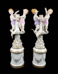 DRESDEN  PAR DE GRANDES CASTIÇAIS EM PORCELANA DECORADOS COM FIGURAS DE MENINO E MENINA. FUSTES COM ELEMENTOS VEGETALISTAS EM RELEVO. ASSENTE SOBRE SUNTUOSAS BASES REMATADAS EM OURO E DECORADAS COM GUIRLANDAS FLORAIS APLICADAS EM ESMALTE. ALEMNHA, INICIO DO SEC. XX. 53 CM DE ALTURA