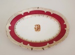 CORONEL JOÃO PINTO DA FONSECA GUIMARÃES. GRANDE TRAVESSA EM PORCELANA COM BORDA DECORADA EM ROSE POMPADOUR REMATADA FOR FINO OURO EM GUIRLANDAS. RESERVAS COM INICIAIS ENTRELAÇADA JP. PERTENCEU AO SERVIÇO DO CORONEL JOÃO PINTO DA FONSECA GUIMARÃES. FRANÇA, MEADOS DO SEC. XIX. 45 CM DE COMPRIMENTO.