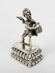 BELO SINETE EM PRATA DE LEI. ESTILO E ÉPOCA ART NOUVEAU. PEGA COM REPRESENTAÇÃO DE FIGURA DO DEUS CUPIDO SEGURANDO CAIXA DE ABELHA E PROVANDO O MEL. SOB A CAIXA UMA ABELHA POUSADA. EUROPA, SEC. XIX. 5,5 CM DE ALTURA