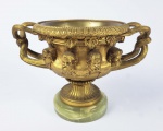 GRANDE CENTRO DE MESA EM BRONZE ORMOLU  SOBRE BASE EM ONIX.  COM FEITIO DE TAÇA DECORADO EM RELEVO COM FIGURAS DOS GRANDES FILÓSOFOS PLATÃO, SÓCRATES, ARISTÓTELES E KANT. ALÇAS LATERAIS FORMADAS EM TORCITURA. EUROPA, INICIO DO SEC. XX. 30 CM DE DIAMETRO