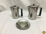 Lote composto de bule, leiteira e manteigueira em aço inox Wolff, recipiente da manteigueira em cristal lapidado. Medindo o bule 17,5cm de altura.