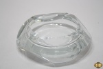 Cinzeiro redondo em bloco de vidro moldado. Medindo 16cm de diâmetro x 4,5cm de altura. Peça com leves bicados.