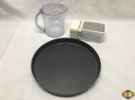 Lote composto de tabuleiro redondo, ralador com pote e jarra com medidor. Medindo o tabuleiro 29cm de diâmetro x 4cm de altura.