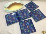 Travessa retangular em porcelana na forma de peixe com 5 pratos em melanina com estampa de peixes. Medindo a travessa 39,5cm x 26,5cm.