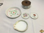 Lote composto de descansos de copo, descanso de garrafa, petisqueira e açucareiro, em porcelanas diversas. Medindo o descanso de garrafas 16,5cm de diâmetro.