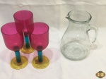 Lote composto de 3 taças em plástico colorido e jarra para água sucos em vidro incolor. Medindo as taças 19,5cm de altura.