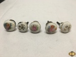 Jogo de 5 puxadores em porcelana pintada com acabamento em metal.
