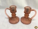 Par de palmatórias em vidro salmão moldado. Medindo 16,5cm de altura x 12cm de diâmetro de base, uma delas tem uma trinca interno no pescoço