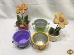 Lote composto de 4 cachepots em metal colorido e 1 em cerâmica pintada com 2 flores em madeira pintada. Medindo os cachepot em metal 9cm de altura.
